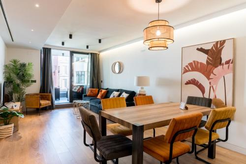 uma sala de estar com uma mesa de madeira e cadeiras em Apartmentsole - San Pablo em Sevilha