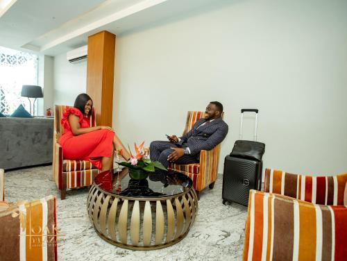 two people sitting in chairs in a living room at Oak Plaza Hotels East Airport in Accra