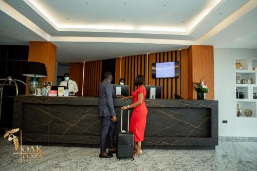 a man and a woman standing in front of a counter at Oak Plaza Hotels East Airport in Accra