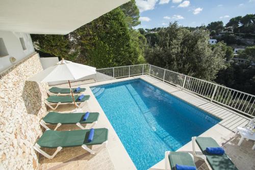 a swimming pool with chaise lounge chairs and a villa at Miramar L by Sonne Villas in Cala Galdana