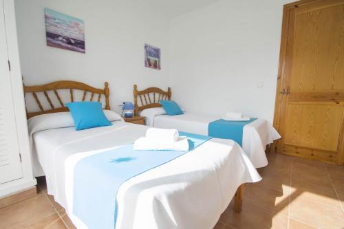 a room with two beds with white and blue at Miramar L by Sonne Villas in Cala Galdana