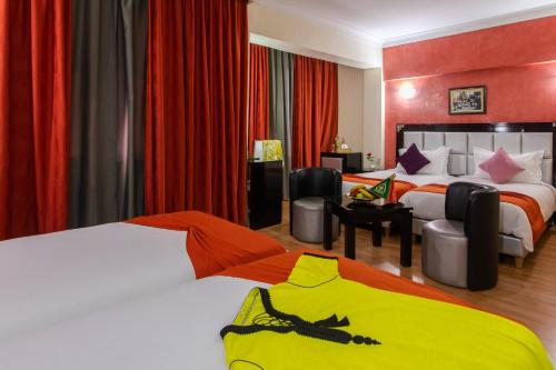 a hotel room with two beds with red curtains at Hotel Meriem Marrakech in Marrakech