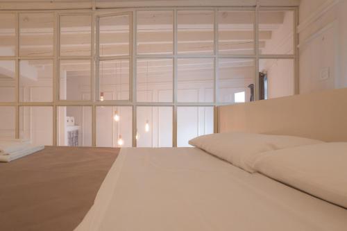 a white bed in a room with glass windows at Loft prestigioso nel centro di Sanremo in Sanremo