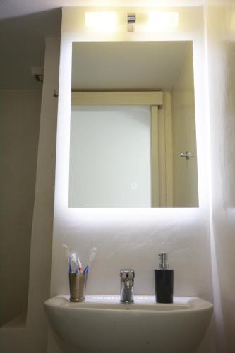 a bathroom sink with a mirror and toothbrushes at Cozy Centrale in Tinos Town