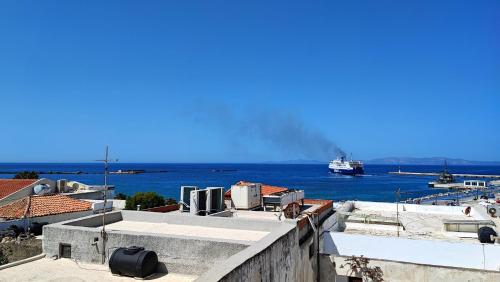 a boat in the water with a ship in the distance at Cozy Centrale in Tinos Town