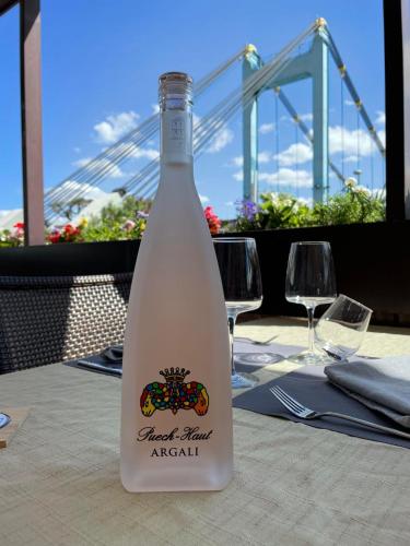 a bottle of wine on a table with a bridge in the background at Logis Hotel Schaeffer- Restaurant Le Saint Georges in Serrières