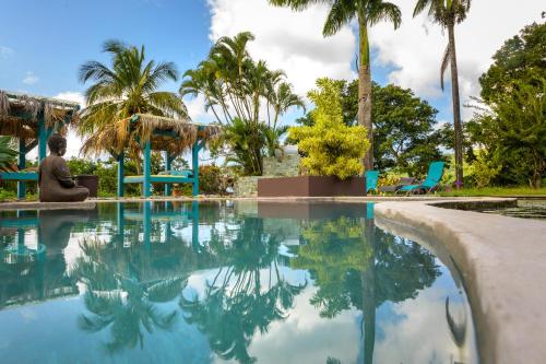 a woman sitting next to a swimming pool with palm trees at TropicAngel ECOLODGE de Charme in Pointe-Noire