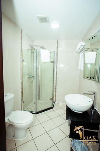 a bathroom with a shower and a toilet and a sink at Oak Plaza Hotels East Airport in Accra