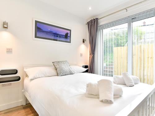 ein Schlafzimmer mit einem großen weißen Bett und einem Fenster in der Unterkunft Pass the Keys Newly Renovated Bungalow - Stunning views of Gower in Swansea