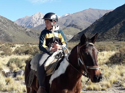 a young boy riding a horse in the mountains at Base Manzano in Tunuyán