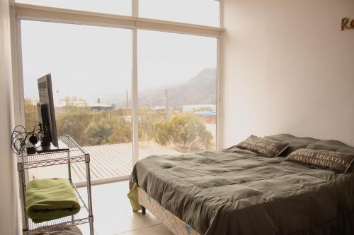 a bedroom with a bed and a large window at Piuquenes Potrerillos in Potrerillos