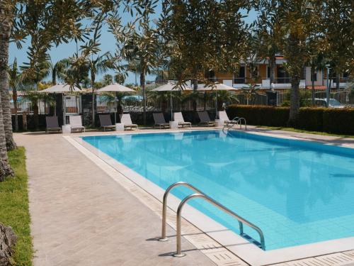 a large swimming pool with chairs and umbrellas at Villa Galati Resort in Mascali