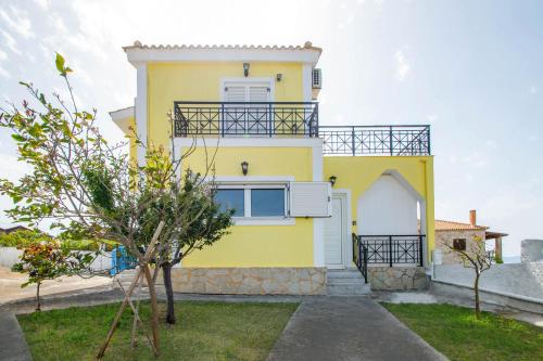 a yellow house with a balcony at Villa Gousetis on the Beach in Zakynthos Town