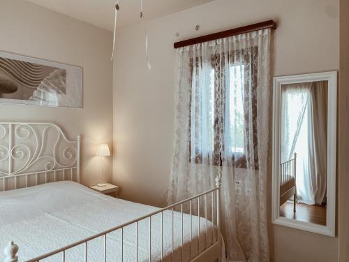 a white bedroom with a bed and a window at Luxury 3BR Sunrise Villa , Seaside Gyrismata in Skiros
