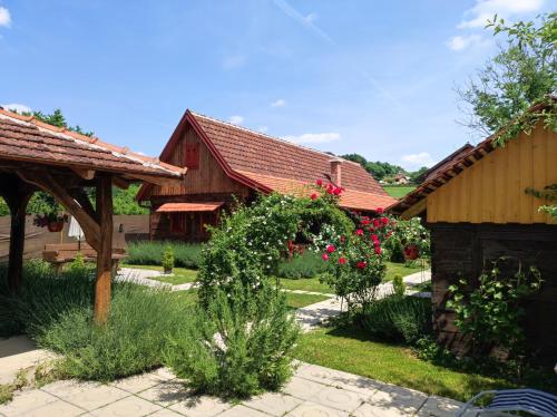 a house with a garden with roses in the yard at Pod orehom drvena kuća i sauna in Krapina