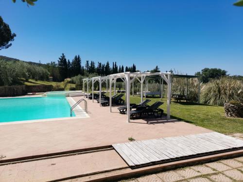 a pool with chairs and a pavilion next to at Il Rosmarino Appartamenti in Scarlino