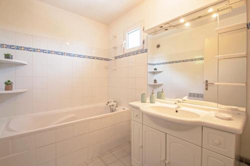 a white bathroom with a tub and a sink and a bath tubermott at Duplex toit terrasse vue panoramique in Montpellier