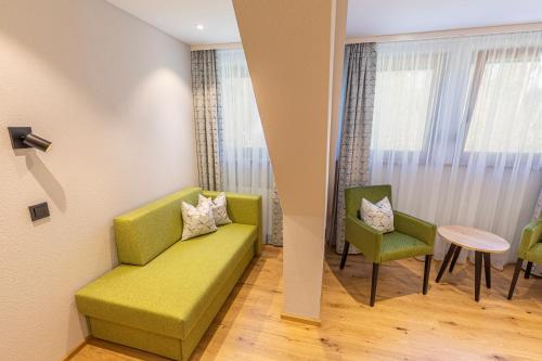 a living room with a green couch and two chairs at Landhaus Lauble in Hornberg