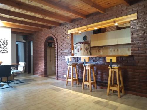 - une cuisine avec un mur en briques et un bar avec tabourets dans l'établissement Casa Perez, à San Martín de los Andes