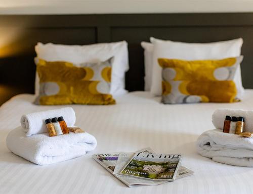 a white bed with towels and magazines on it at The Bell Inn Hotel in Lyndhurst