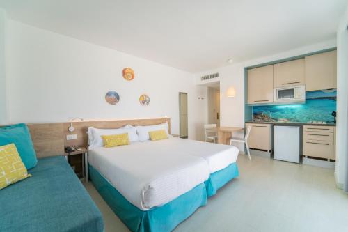 a bedroom with a large bed and a kitchen at Apartamentos Ferrer Lime Tamarindos in Port d'Alcudia