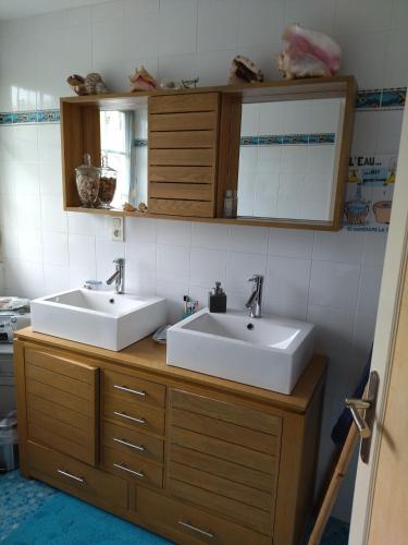 La salle de bains est pourvue de 2 lavabos et de placards en bois. dans l'établissement Chambre Solo Grande maison, à Gouesnou