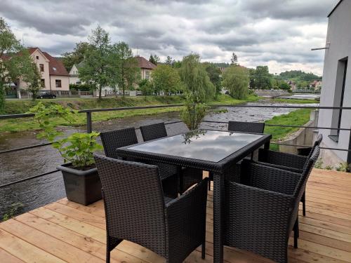 einen Tisch und Stühle auf einer Terrasse mit Flussblick in der Unterkunft Rezidence Valcha in Sušice