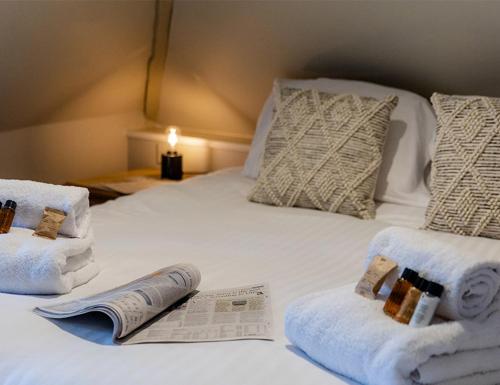 a white bed with towels and a newspaper on it at The Bell Inn Hotel in Lyndhurst