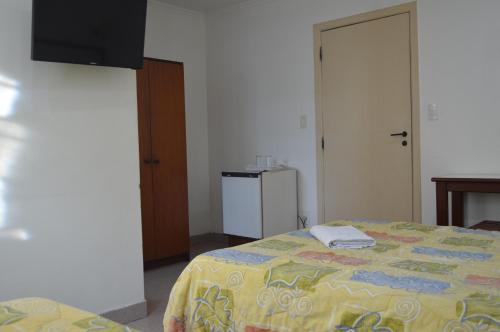 a bedroom with a bed and a small refrigerator at Hotel Brasil Pindamonhangaba in Pindamonhangaba