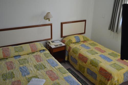 a bedroom with two beds and a table with a mirror at Hotel Brasil Pindamonhangaba in Pindamonhangaba
