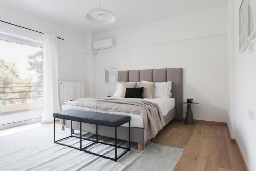 a white bedroom with a bed and a table at Stellar 3BR Apartment with Balcony by UPSTREET in Athens