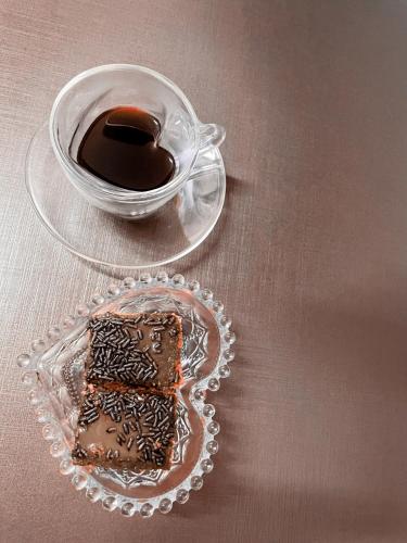 a glass plate with a piece of chocolate and a cup of coffee at Tezla Hotel in Primavera do Leste