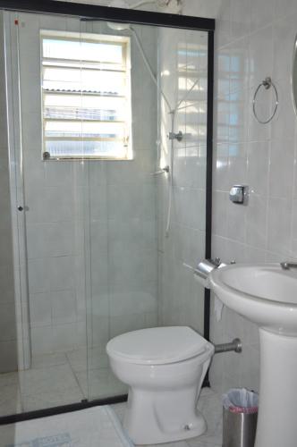 a bathroom with a shower and a toilet and a sink at Hotel Brasil Pindamonhangaba in Pindamonhangaba