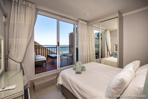 a bedroom with a bed and a large window at Twin Tide Duplex in Umdloti