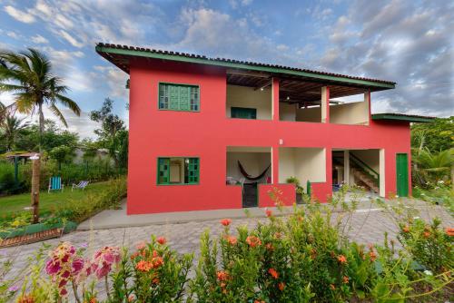 una casa roja con un jardín delante en Casarão das artes hospedaria en Cumuruxatiba