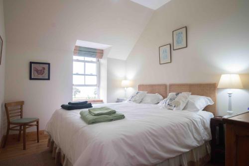 a bedroom with a large white bed with a window at Steading Cottage - 50m from the beach in Port Appin