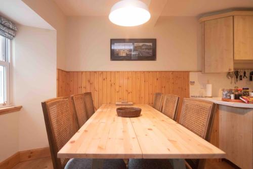 a wooden table in a kitchen with chairs around it at Steading Cottage - 50m from the beach in Port Appin