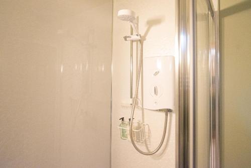 a shower in a bathroom next to a refrigerator at Steading Cottage - 50m from the beach in Port Appin
