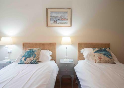two beds sitting next to each other in a bedroom at Steading Cottage - 50m from the beach in Port Appin