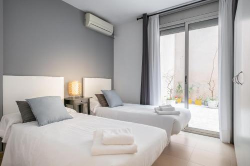 2 białe łóżka w pokoju z oknem w obiekcie Inside Barcelona Apartments Salva w Barcelonie