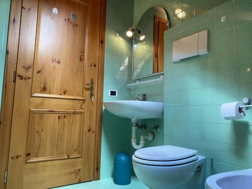 a bathroom with a wooden door and a toilet and sink at Condominio Gaiolin in Giustino