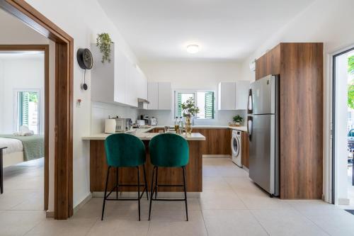 a kitchen with white cabinets and green bar stools at Arty Haven - Spacious 3-BR House in Larnaca in Larnaca