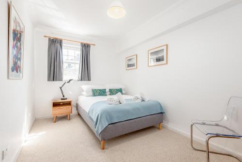a white bedroom with a bed and a chair at Abbey Street - 2 bedroom - Central in St. Andrews