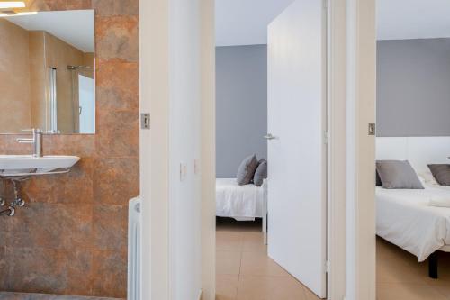 a bathroom with a sink and a mirror and two beds at Inside Barcelona Apartments Salva in Barcelona