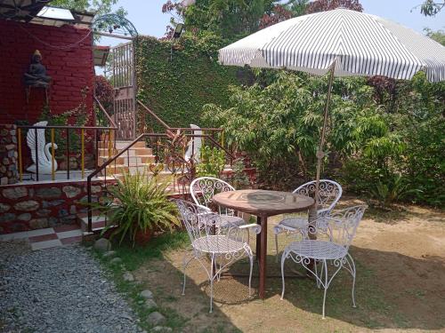a table and chairs with an umbrella in a yard at Oxygen Homestay-A Blissful Retreat in Dehradun