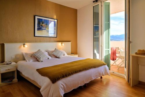 a bedroom with a large bed and a balcony at Hôtel Du Golfe in Ajaccio