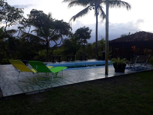 a swimming pool with two green chairs next to it at Nossa Senhora Aparecida in Marau