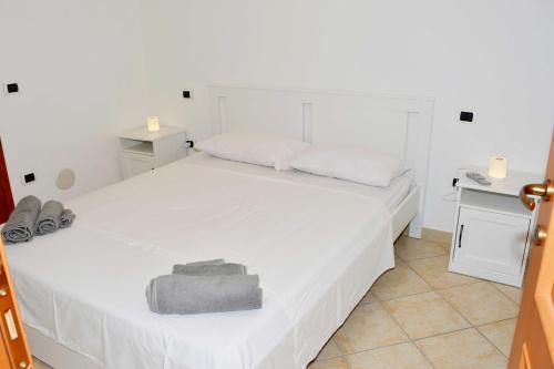 - une chambre avec un lit blanc et une serviette grise dans l'établissement Residence Nausicaa, à Santa Teresa Gallura