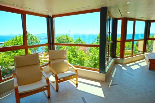 a room with two chairs and large windows at Paradise Hotel & Relax Center in Pomorie