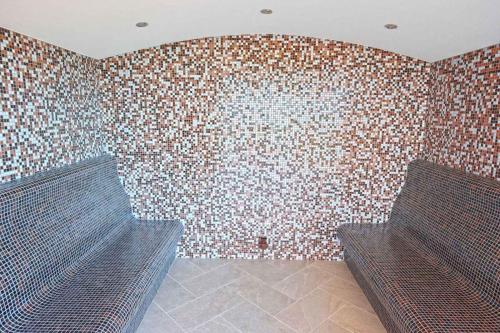 two benches in a room with a brick wall at Paradise Hotel & Relax Center in Pomorie